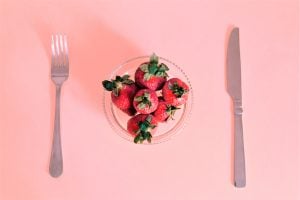plate of strawberries on a pink background