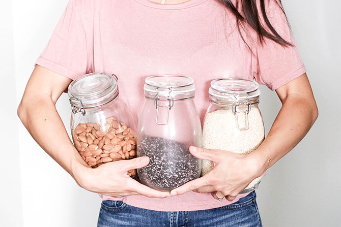 girl holding a jar of almonds, seeds, and salt